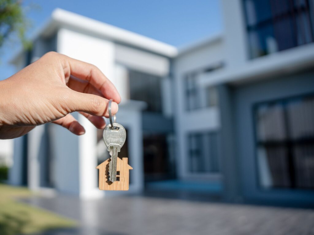 Hand holding a house key with home in the background, first home buyer concept in Bundaberg
