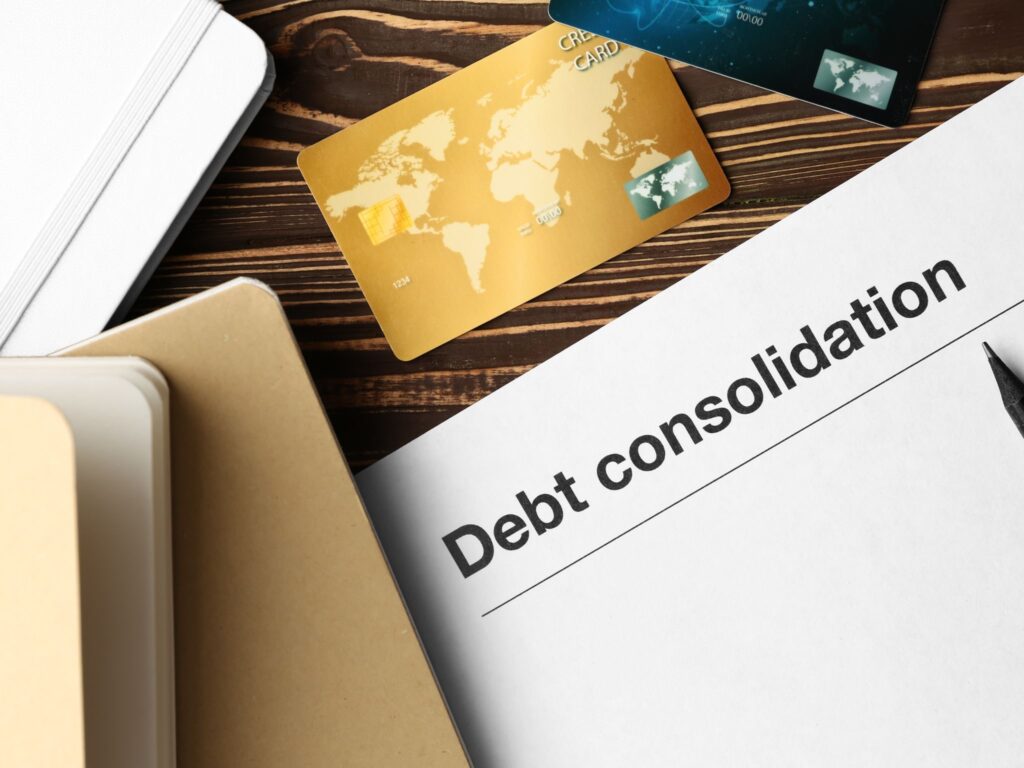 Scattered documents on the table showing folders, a paper with "debt consolidation", and a credit card.